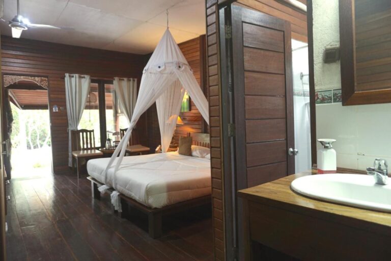 A double room with a bed under a mosquito net, and a sink in the foreground