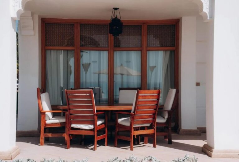 A covered terrace with a wooden table and six chairs, under a lantern