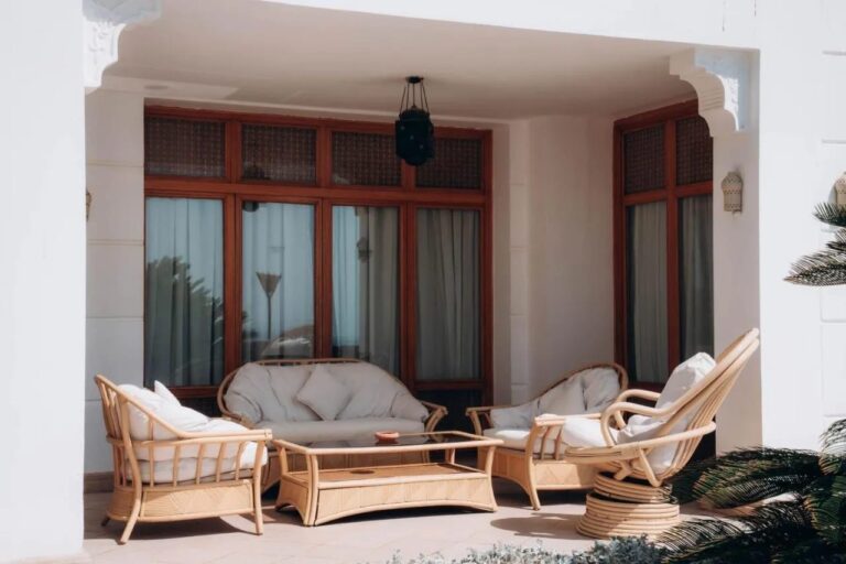 A covered terrace with a rattan sofa and armchairs
