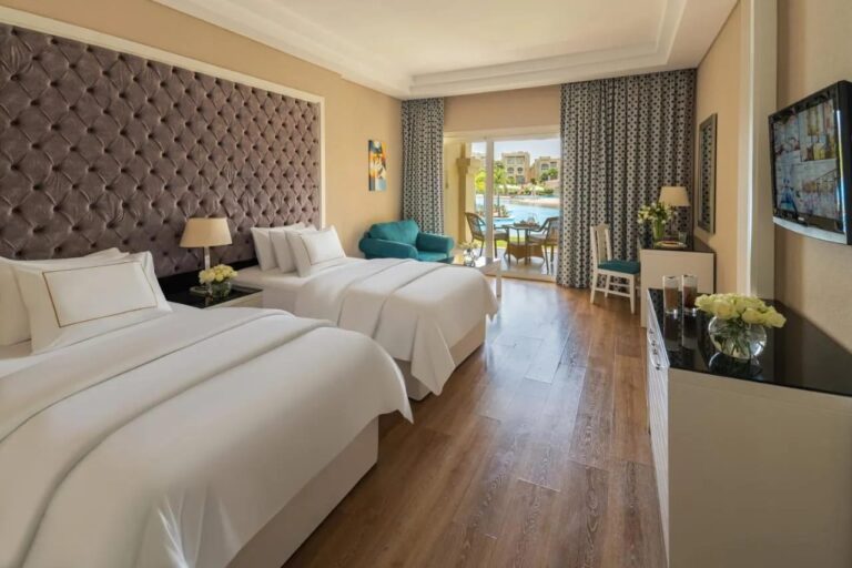 A room with two double beds and a wooden floor, opening onto the pool