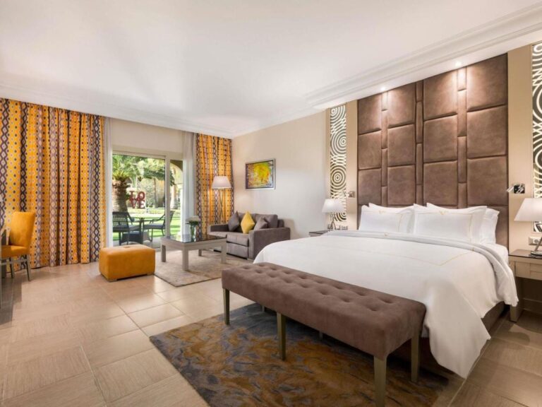 A room with a double bed, a seating area and a French window onto the garden