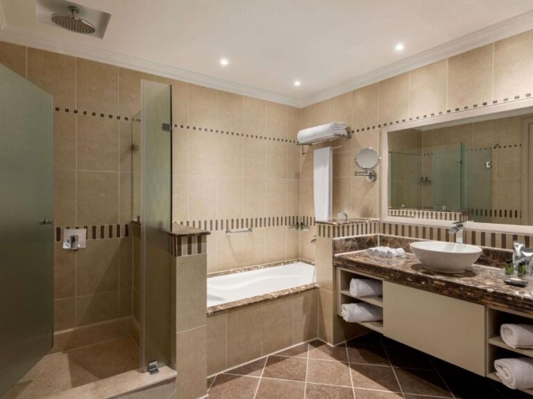 A bathroom with a glass shower, a bathtub and a countertop sink