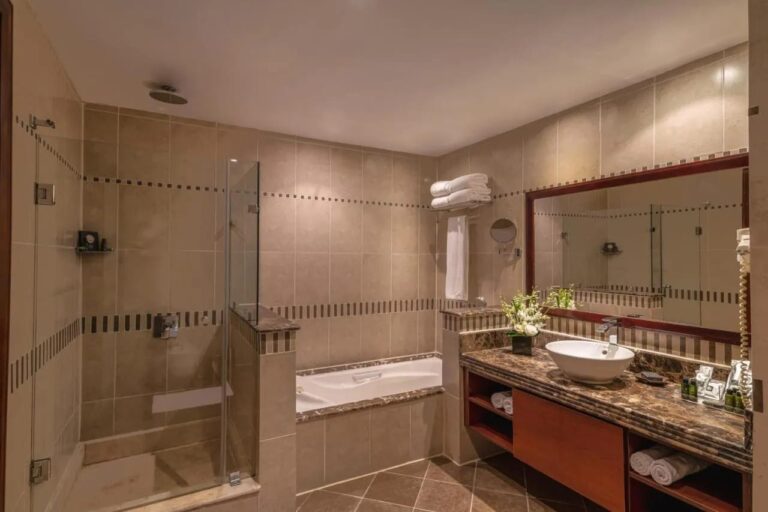 A bathroom with a glass shower, a bathtub and a large mirror