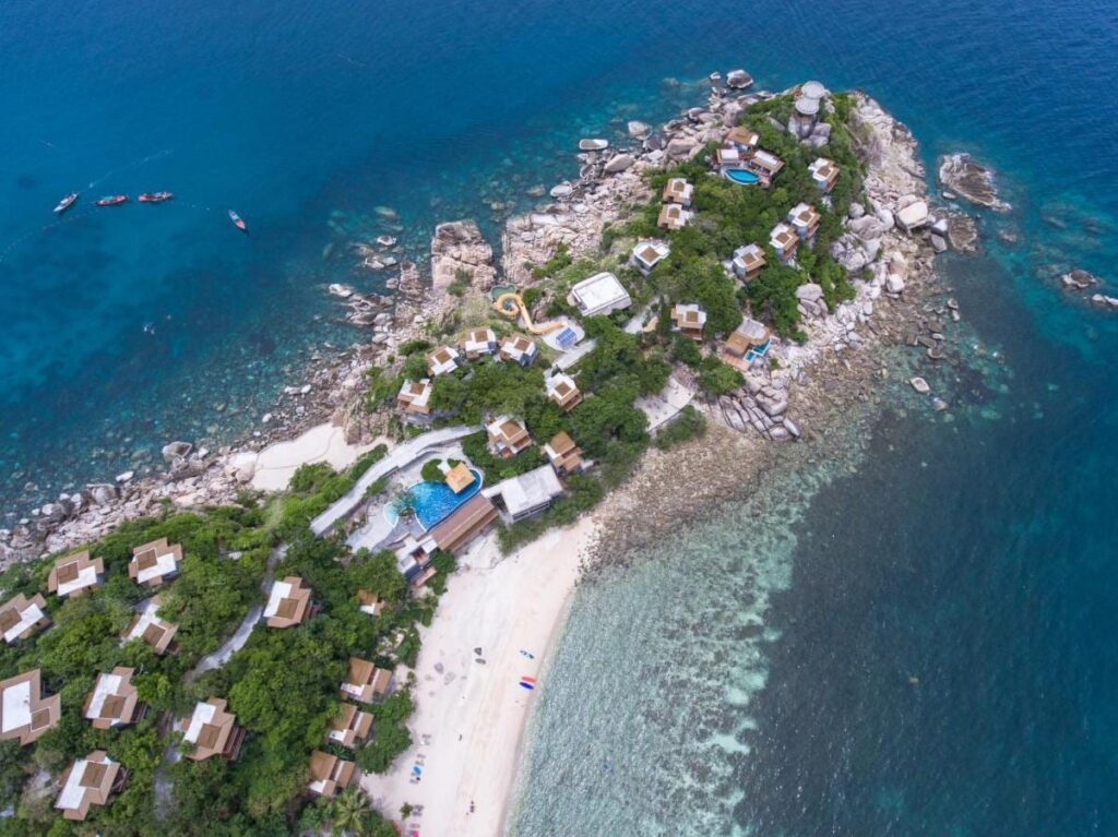 Aerial view of Sai Daeng Resort, with its bungalows on a rocky point, its pools and its sandy beach