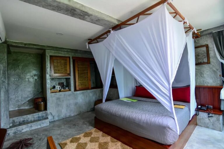 A room with a bed under a mosquito net and a tea corner in a wall niche