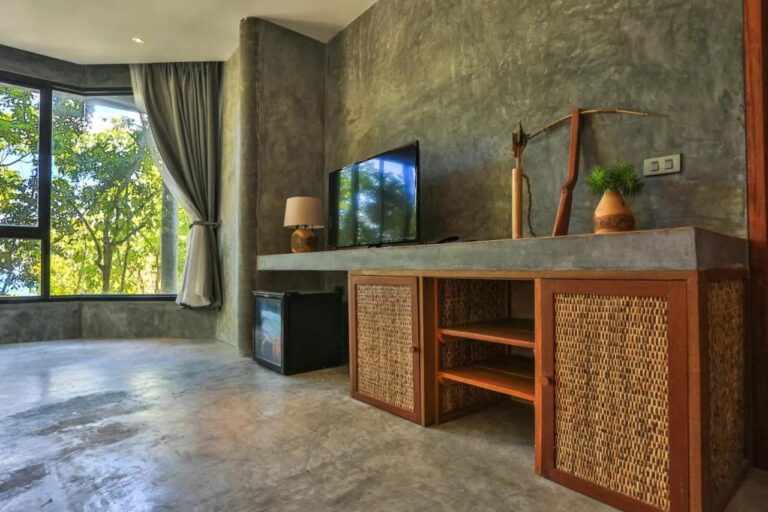 A TV on a wood and rattan cabinet, near a minibar and a picture window
