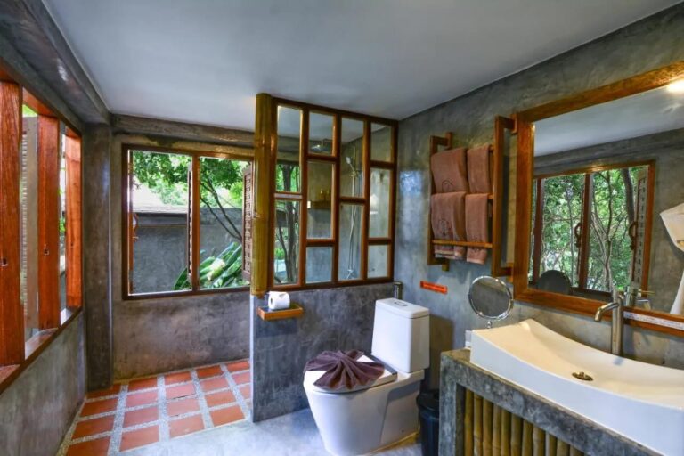 A bathroom with a shower behind a wood-framed glass partition