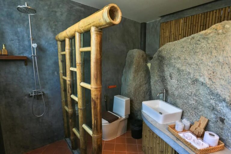 A bathroom built against a large boulder, with a shower and a sink