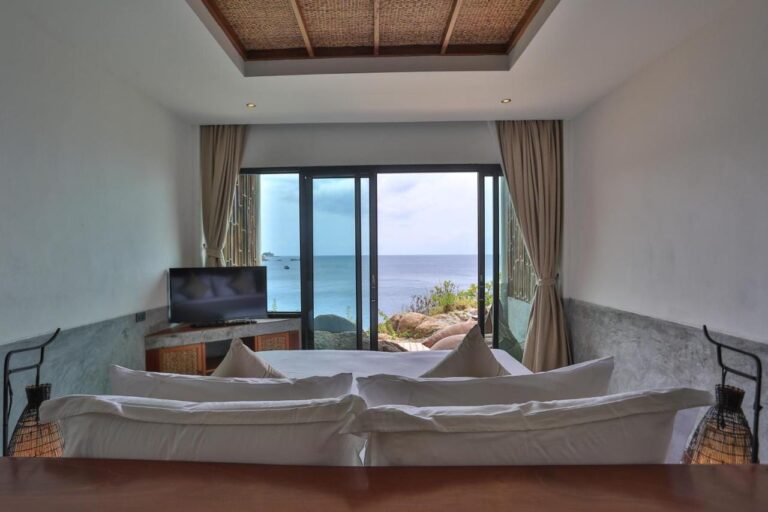 A sea-facing room seen from the head of the bed, with two wicker lamps