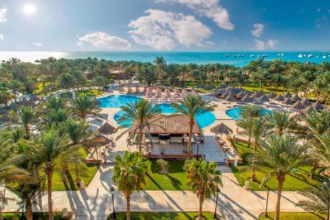 Aerial view of Siva Grand Beach, its pools among the palm trees and the Red Sea with boats at anchor