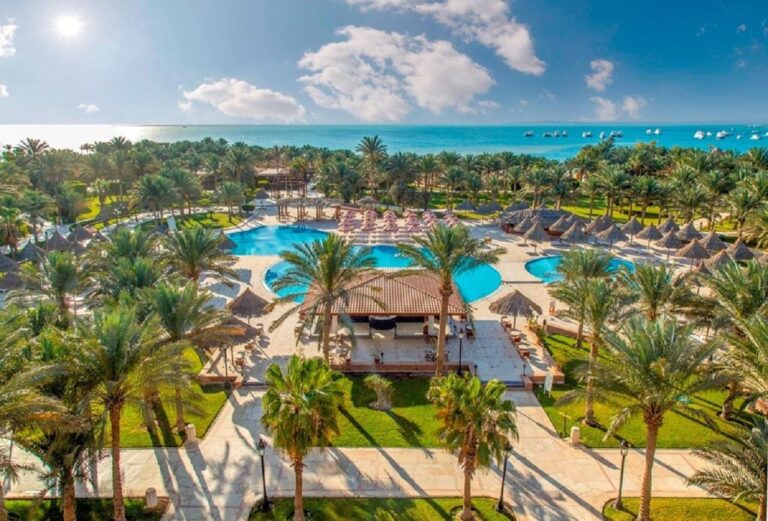 Aerial view of Siva Grand Beach, its pools among the palm trees and the Red Sea with boats at anchor