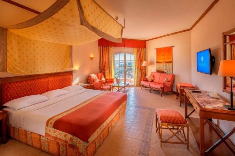 A large room with a canopy bed, an orange sofa and a desk