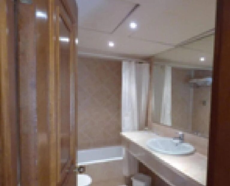 A bathroom with a bathtub, a shower curtain and a long vanity