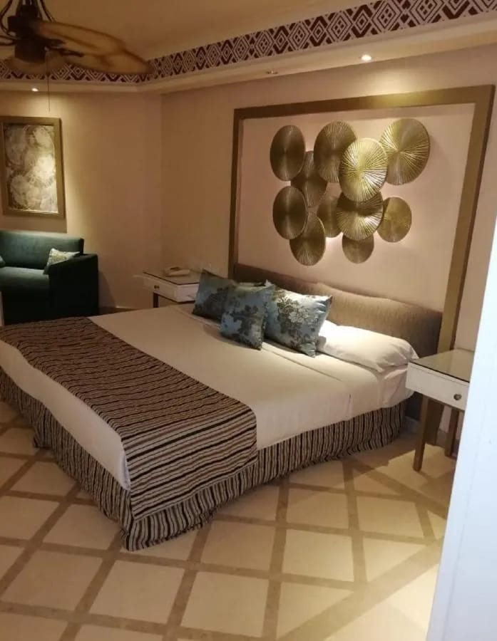 A double bed under a wall decoration of golden discs