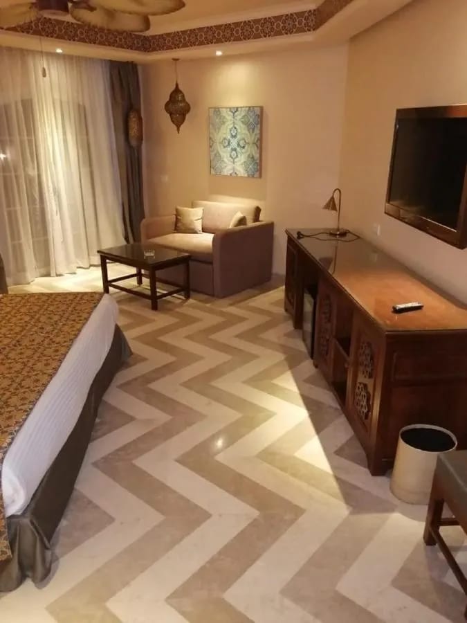 The seating area of a room, with a sofa, a wooden desk and a herringbone floor