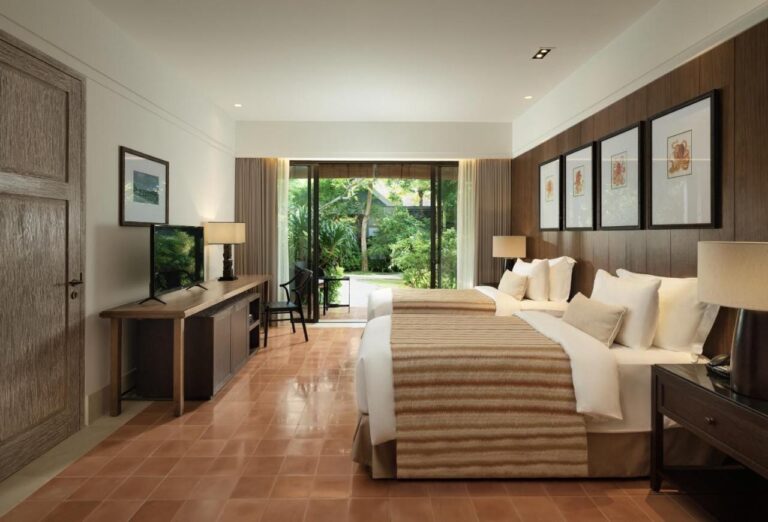 A room with a double bed, a terracotta floor and a picture window onto the garden