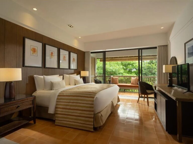 A room with a double bed opening onto a terrace and the garden