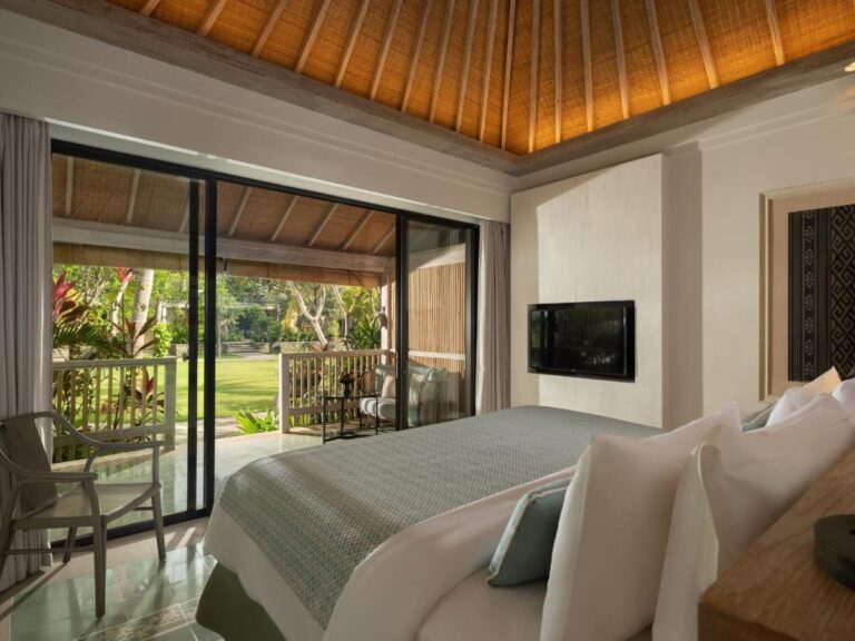 A room under a wooden ceiling, opening onto a terrace and the lawn