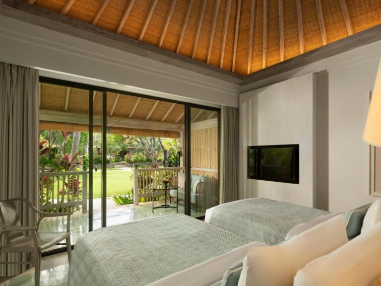 A twin room under a wooden ceiling, with a picture window onto the garden