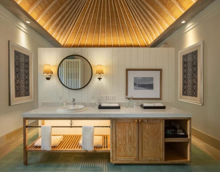 A bathroom with a sink, a round mirror and a wooden cabinet