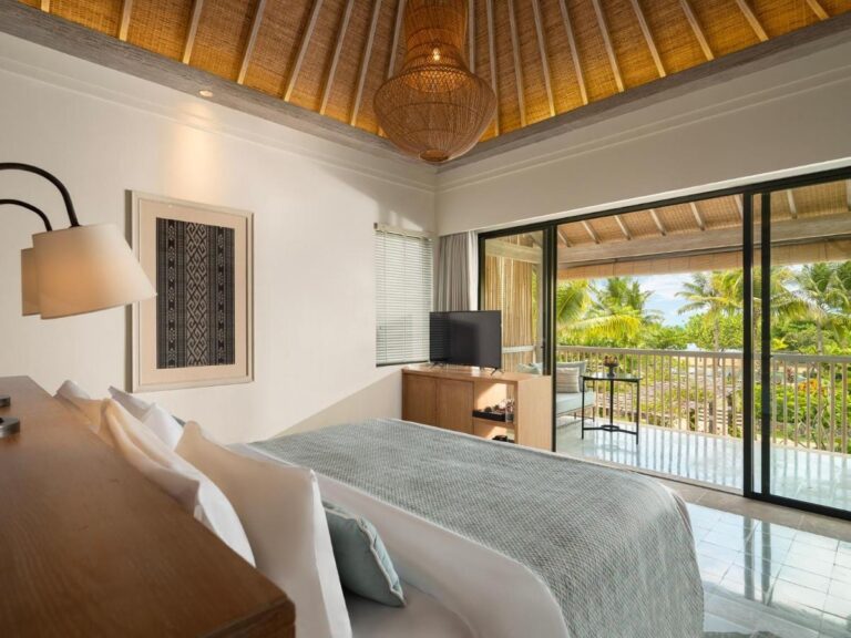 A room opening onto a balcony, with a view of the palm trees