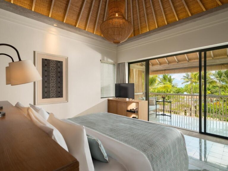 A room with a wicker pendant light and a picture window onto the balcony
