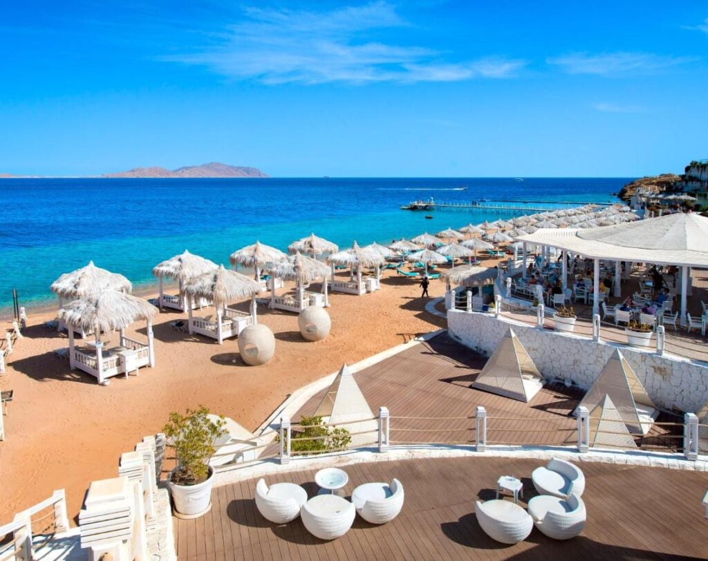The beach at Sunrise Arabian Beach Resort, with its straw parasols and its jetty, facing Tiran Island