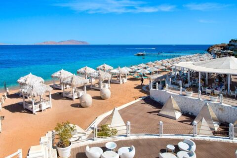 The beach at Sunrise Arabian Beach Resort, with its straw parasols and its jetty, facing Tiran Island