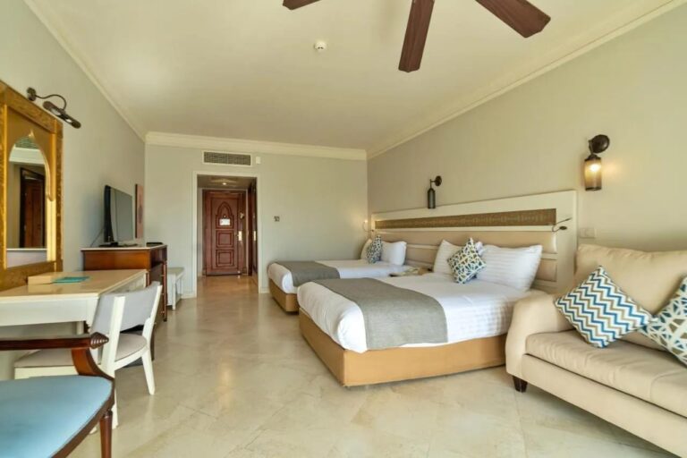 A room with two double beds, a sofa and a ceiling fan