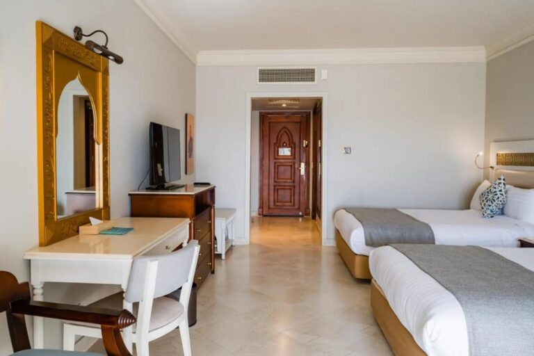 A twin room with a white desk and a golden arch-shaped mirror