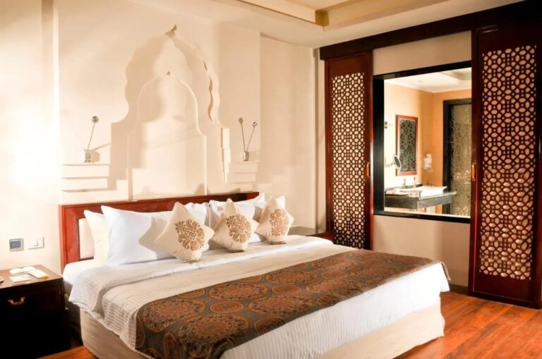 A room with a double bed and openwork wooden panels opening onto the bathroom