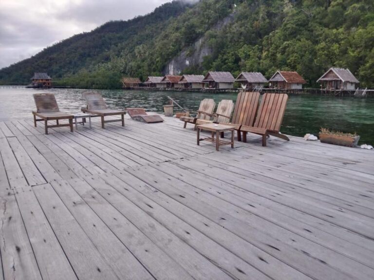 Wooden armchairs and a coffee table on a jetty, facing the cliff and the forest
