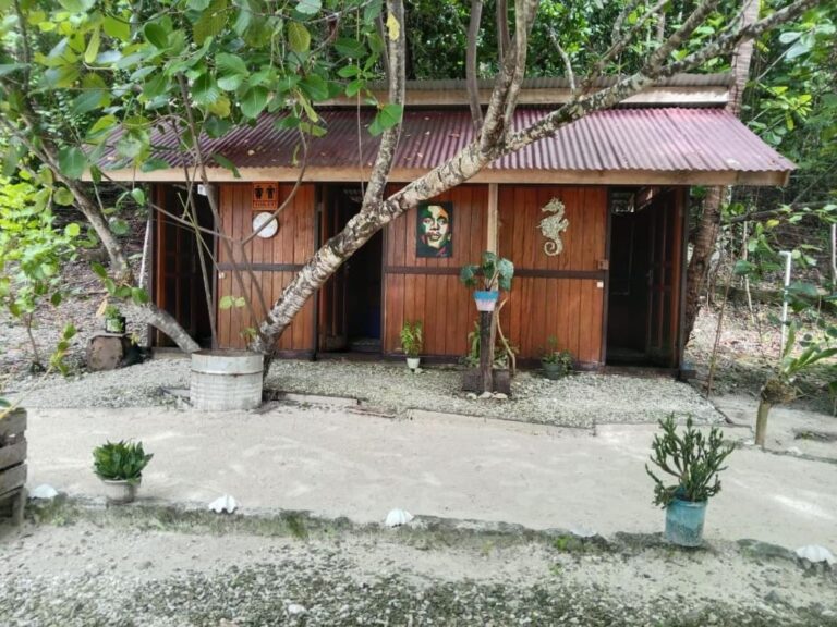 The wooden toilet hut under the trees, with a decorative seahorse