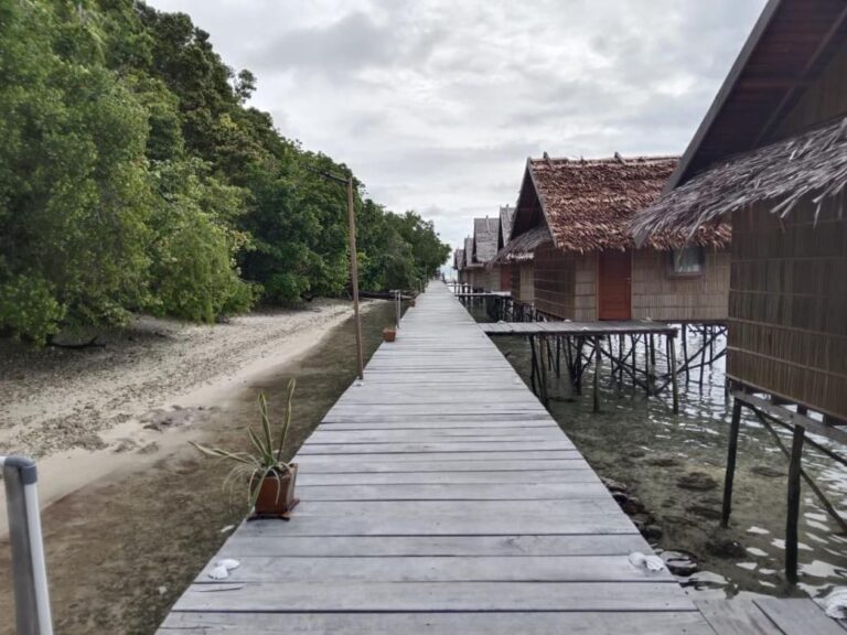 A wooden walkway between the beach and the bungalows on stilts