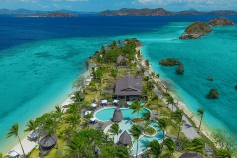 Aerial view of Two Seasons Coron, its pools and palm trees on a narrow strip of land between two beaches