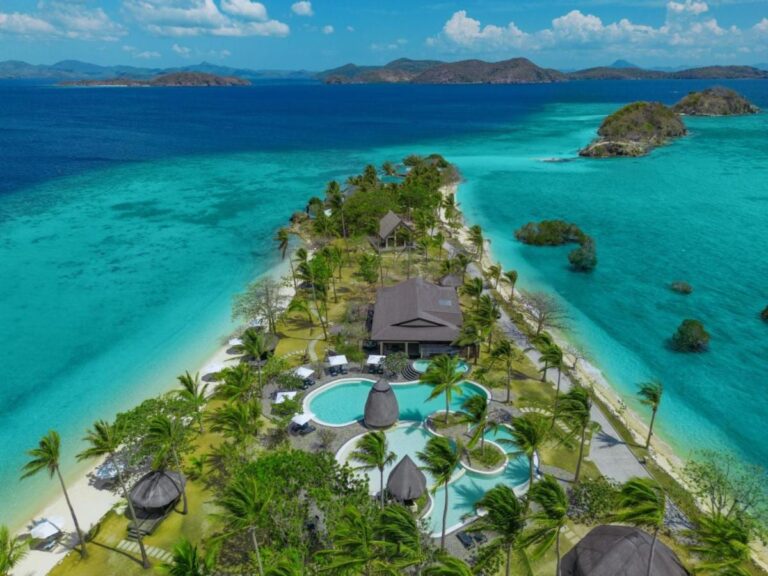 Aerial view of Two Seasons Coron, its pools and palm trees on a narrow strip of land between two beaches