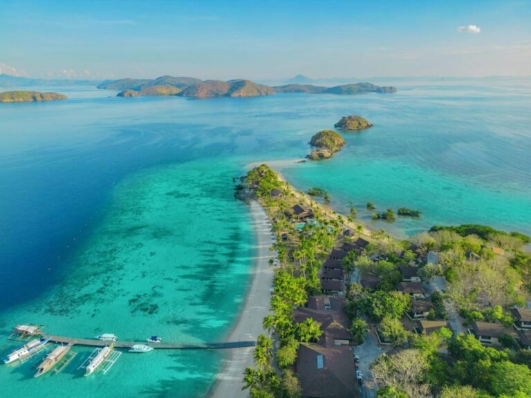 Aerial view of the long beach, the jetty and moored boats, with islets in the distance